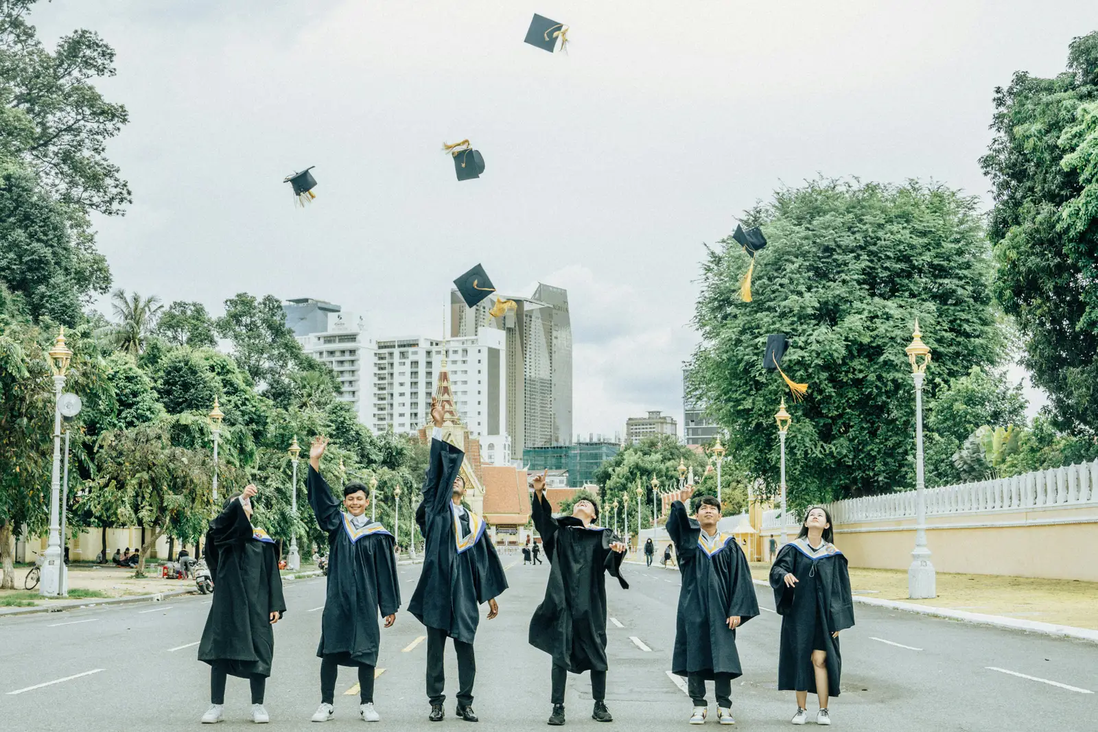 A group of graduates celebrating on a tree-lined street